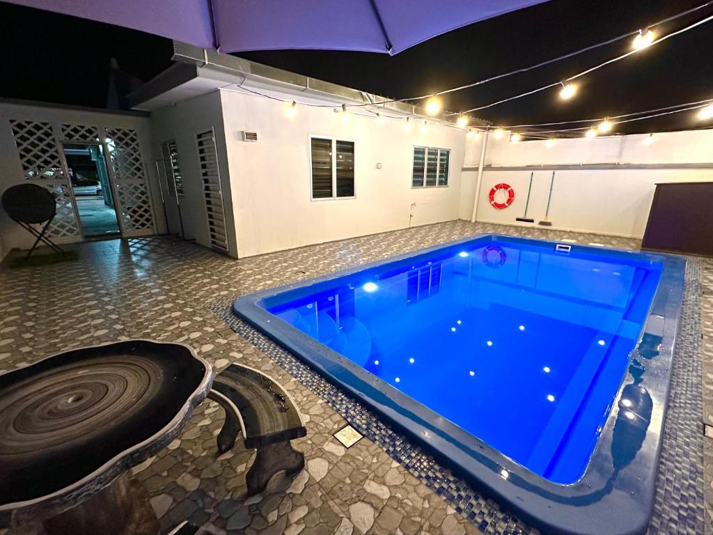 a large swimming pool in a room with an umbrella at Roomah Istana in Ipoh