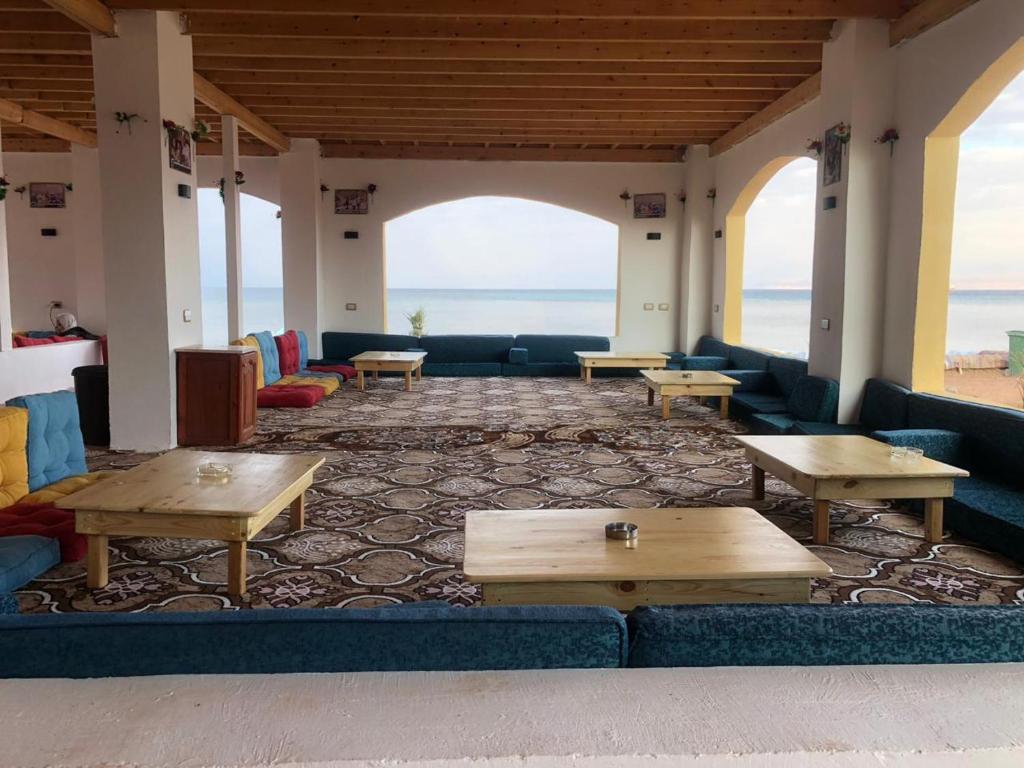 a living room with couches and tables and the ocean at Abo Hamada Azure Camp in Nuweiba