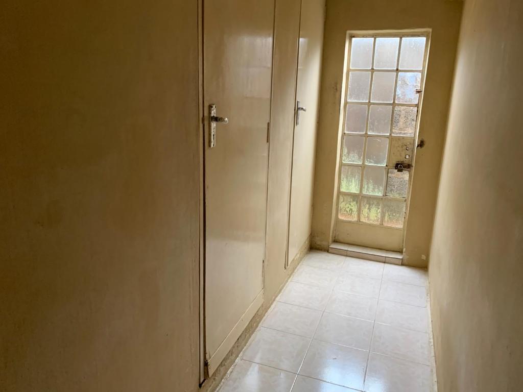 um corredor vazio com uma porta e uma janela em NR appartments em Curepipe