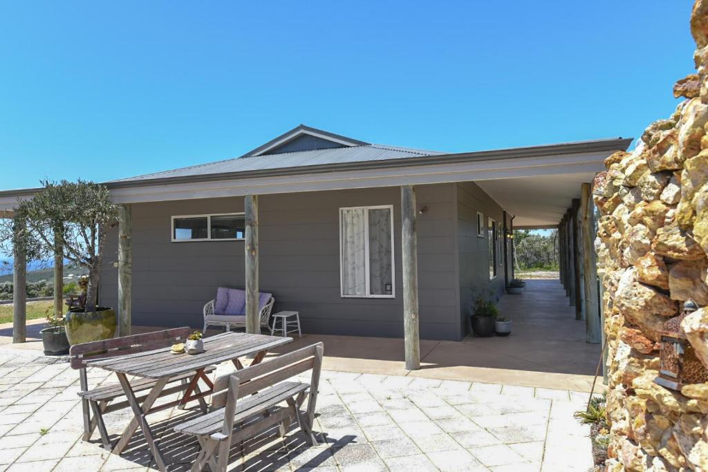a patio with a wooden table and benches on a house at Bremer Bay B&B in Bremer Bay