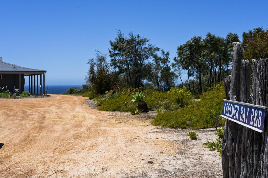 a dirt road with a sign on a fence at Bremer Bay B&B in Bremer Bay