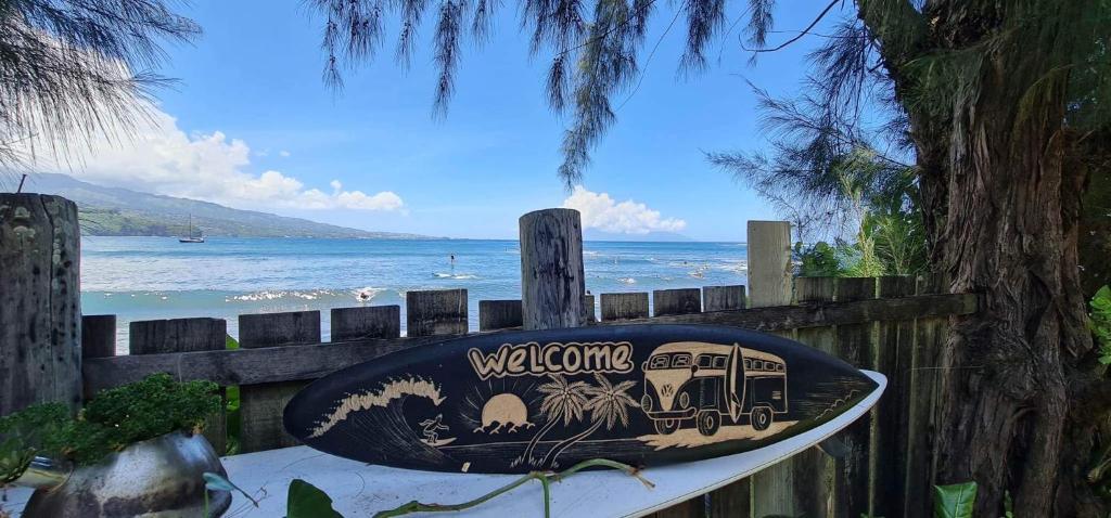 une planche de surf sur une clôture avec l'océan en arrière-plan dans l'établissement Pointe Venus Lodge, à Mahina