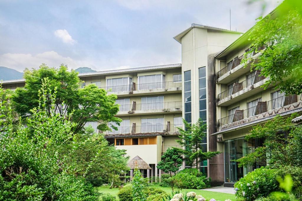 un edificio de apartamentos con árboles delante de él en Yufuin Kotobuki Hananosho, en Yufu