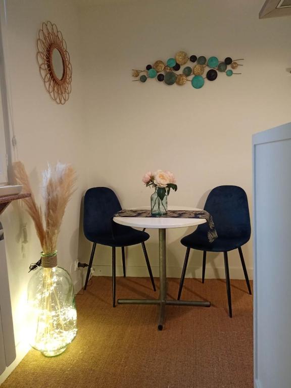 una mesa con dos sillas y un jarrón con flores. en La plus petite maison de pêcheur de Trouville-sur-mer, en Trouville-sur-Mer