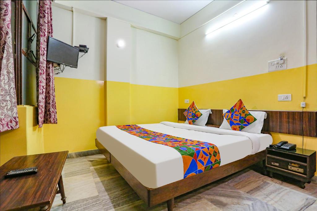 a bedroom with a large bed and a wooden table at FabHotel Ashoka Inn in Kānpur