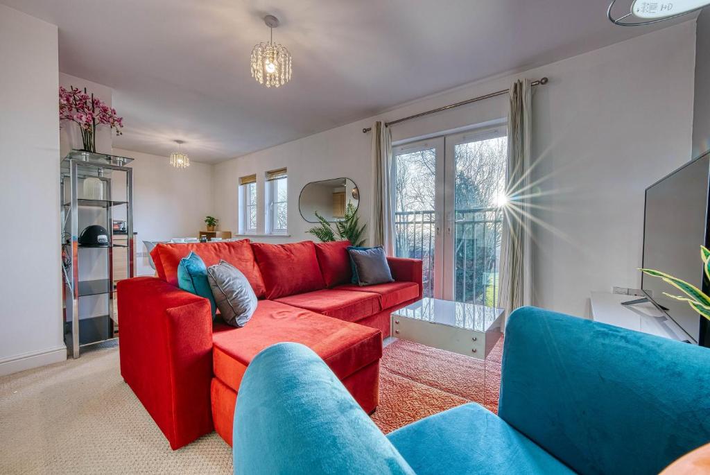 a living room with a red couch and blue chairs at Blue Cedar 2 Bed, 2 Bath Apt with Parking, Birmingham by 360Midlands in Sutton Coldfield