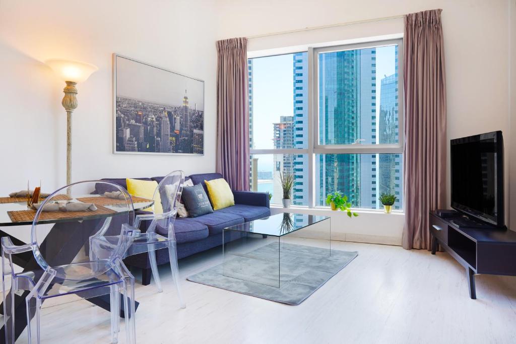 a living room with a blue couch and a glass table at Maison Privee - Stunning Apartment with Dubai Marina View in Dubai