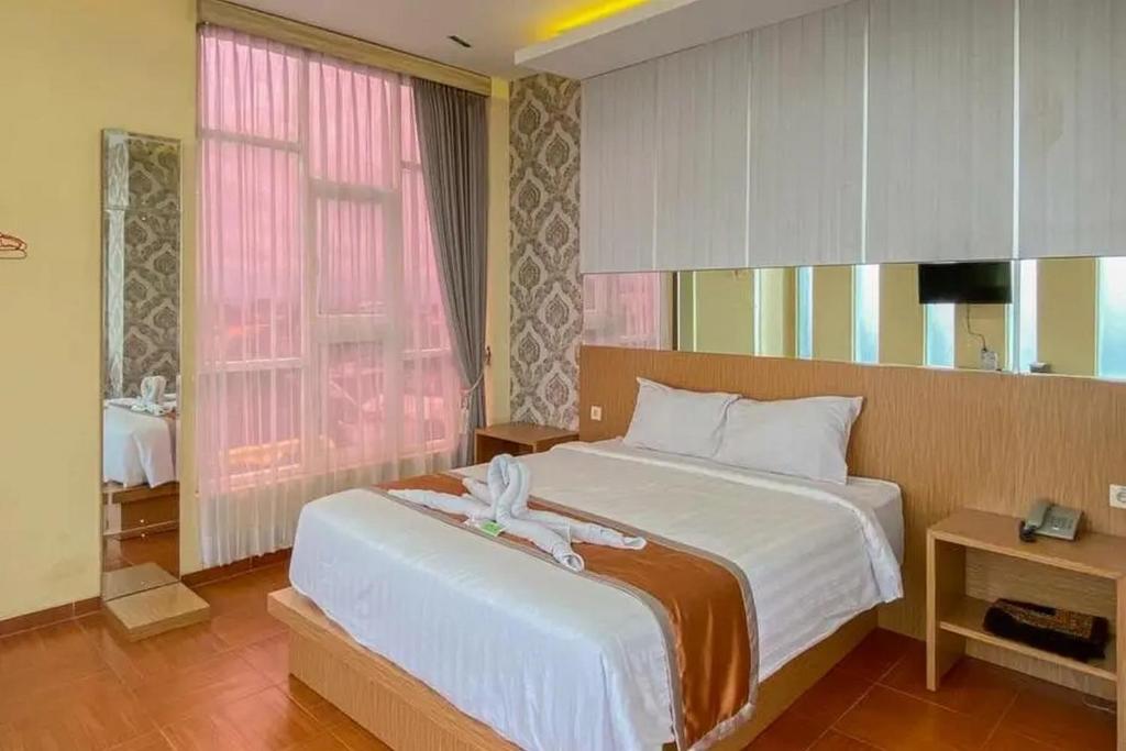 sypialnia z dużym łóżkiem i oknem w obiekcie De Malang Sweet Homestay Syariah Mitra RedDoorz w mieście Malang