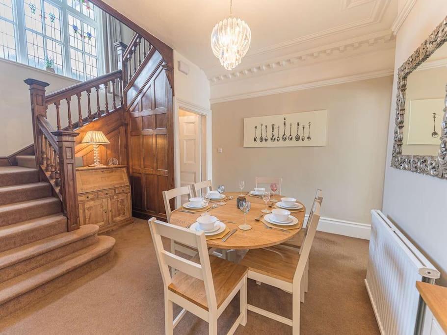 a dining room with a wooden table and a staircase at Southfield is a spacious period five bed, four bath with parking in Kendal
