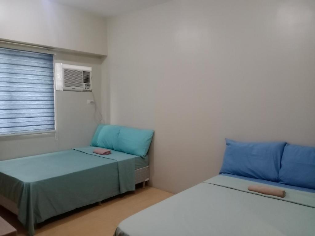 セブシティにあるSunvida Cebuのベッド2台、ソファ、窓が備わる客室です。