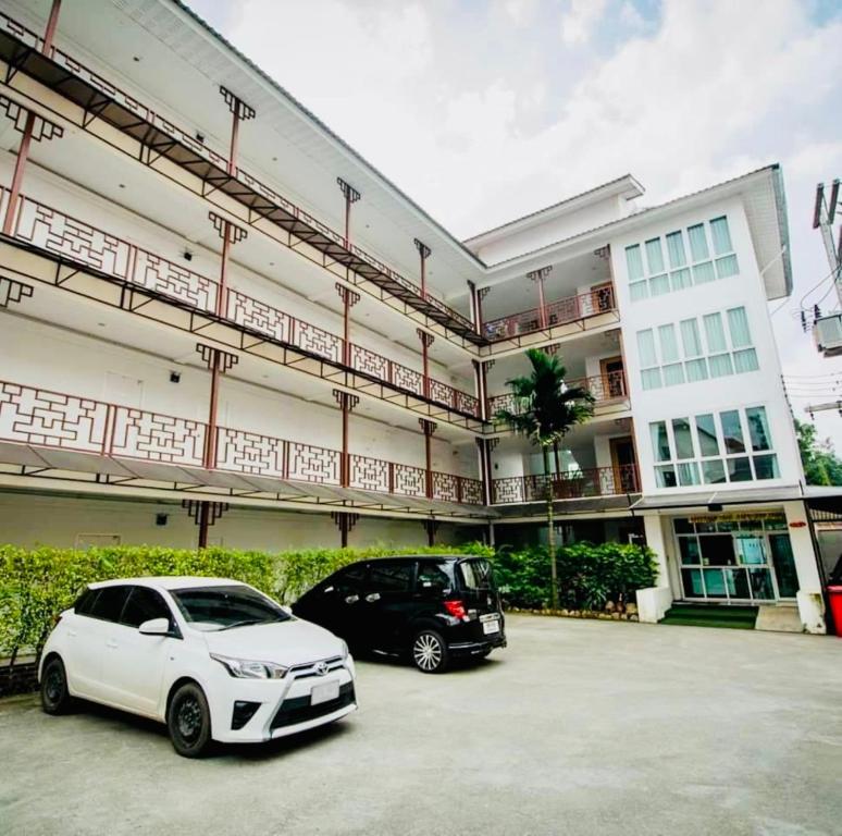 dos autos estacionados en un estacionamiento frente a un edificio en INN Kham Apartment, en Chiang Mai