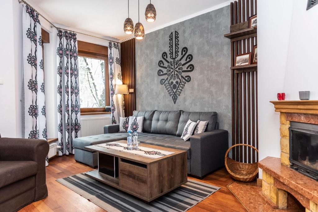 een woonkamer met een bank en een open haard bij TatryTOP Apartamenty Kaszelewski in Zakopane