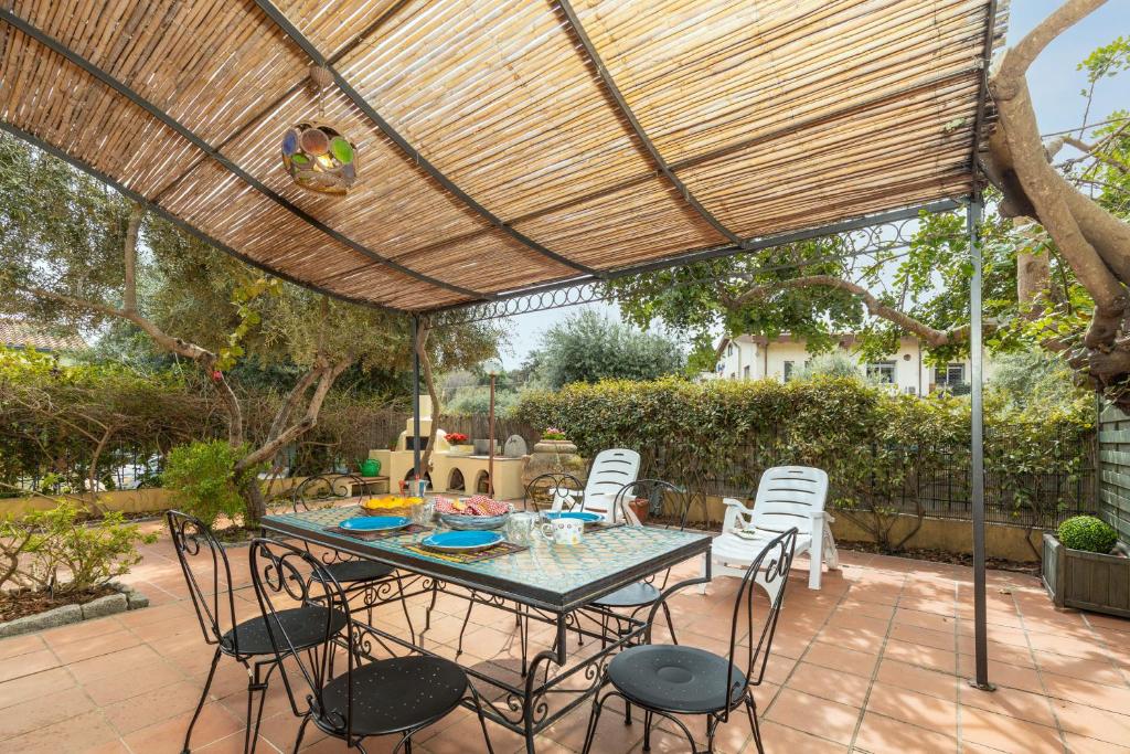 a patio with a table and chairs under a wooden pergola at Casa il grande Carrubo in Santa Maria Navarrese