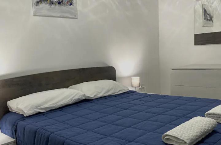 a bed with a blue blanket and white pillows at F1 2 St Julians, Private room, bathroom & living shared in St Julian's