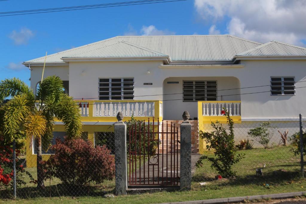 una casa blanca y amarilla con una valla en Villa Benito en Nevis