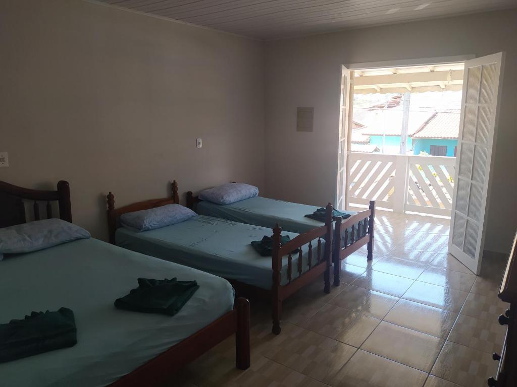 圣塞巴斯蒂安Sobrado Refúgio do Mar - Aconchego e Conforto perto das Praias的客房设有两张床和通往阳台的门。