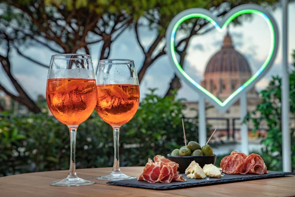 ローマにあるFragrance Hotel St. Peterのワイン2杯、フルーツプレート(テーブルの上)