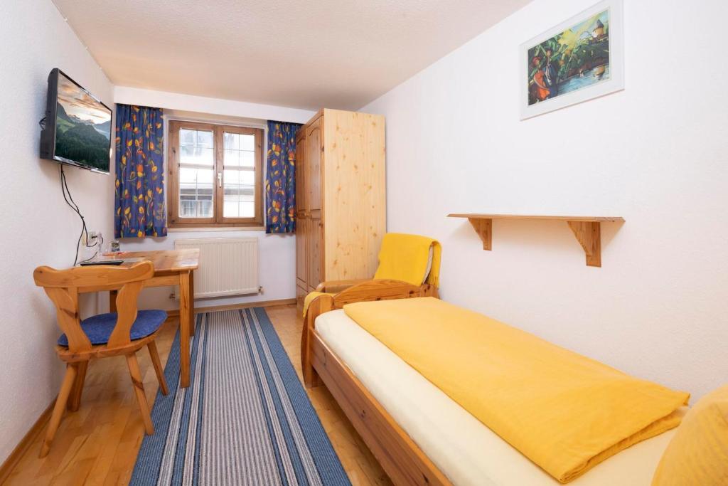 una piccola camera da letto con un letto e una scrivania di Haus Schlosskeller a Rattenberg