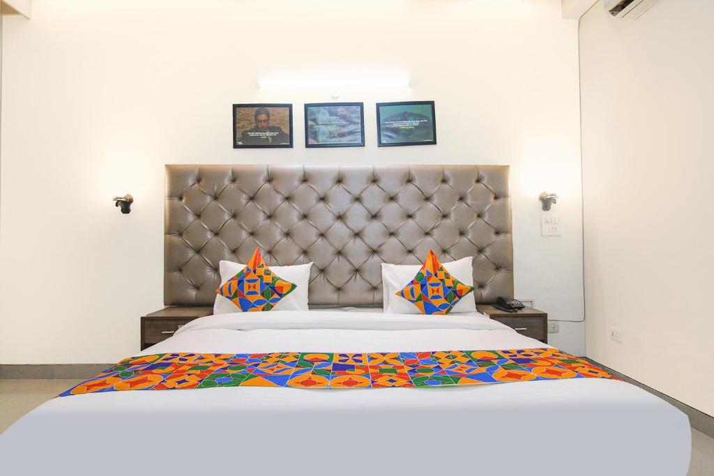 1 dormitorio con 1 cama blanca grande con almohadas coloridas en FabHotel Radiant Inn DLF Phase 3 en Gurgaon