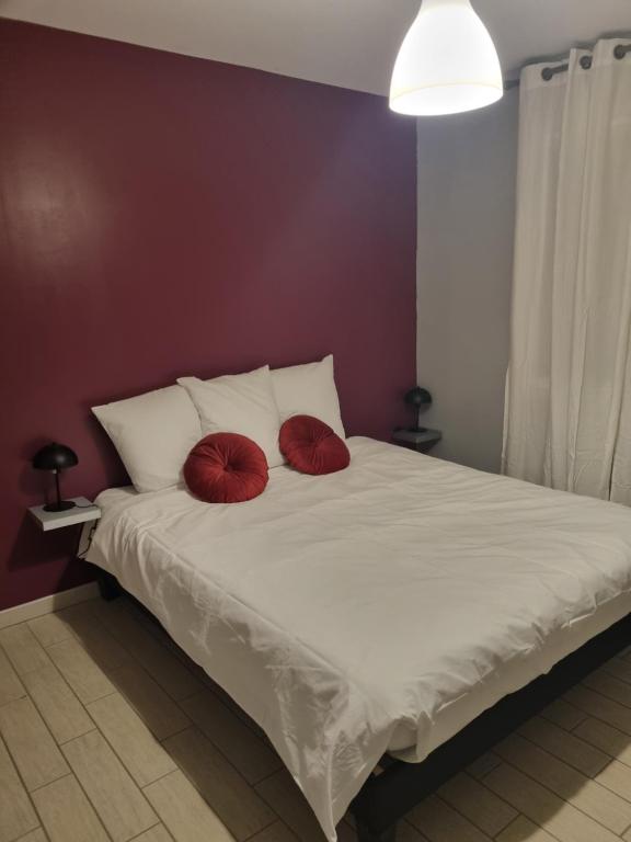 Una cama con dos almohadas rojas encima. en Au cocon de Lin, en Le Neubourg