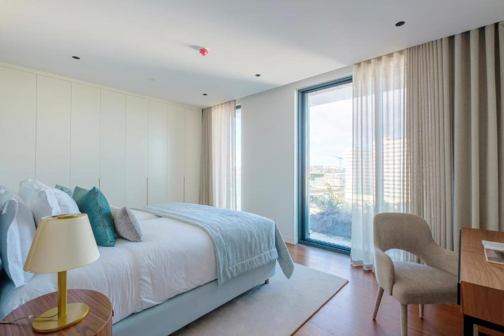a bedroom with a bed and a desk and a window at Martinhal Lisbon Oriente in Lisbon
