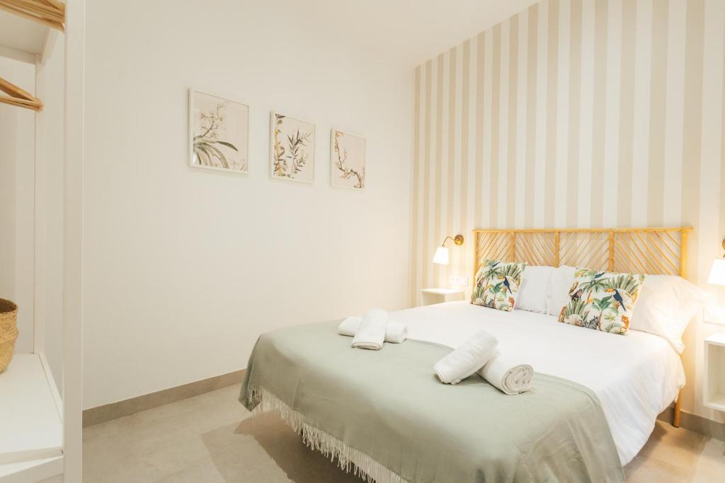 um quarto branco com uma cama com toalhas em Tu casa en un rinconcito del centro em Sevilha