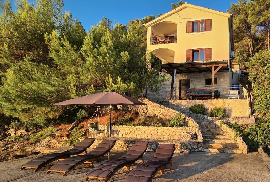 eine Gruppe Stühle und ein Regenschirm vor einem Haus in der Unterkunft Hidden Pearl in Luka