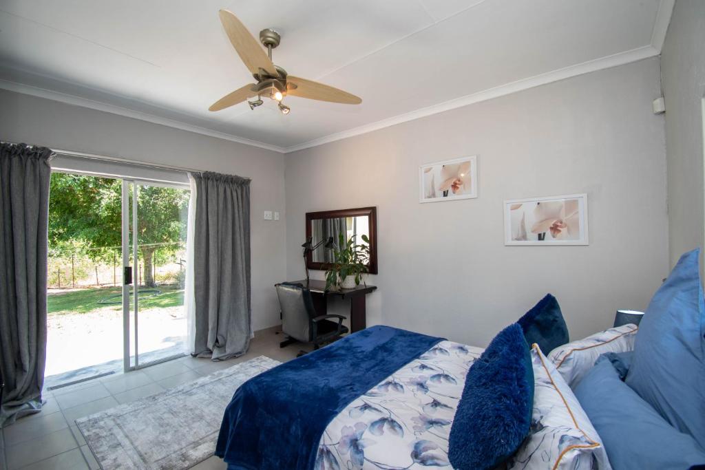 a bedroom with a blue bed and a ceiling fan at Nita's Air Bed & Breakfast & self catering in Crocodile Valley Estates