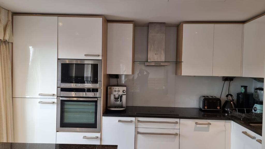 uma cozinha branca com armários e electrodomésticos brancos em Beautiful and modern Apartment in North London em Hendon
