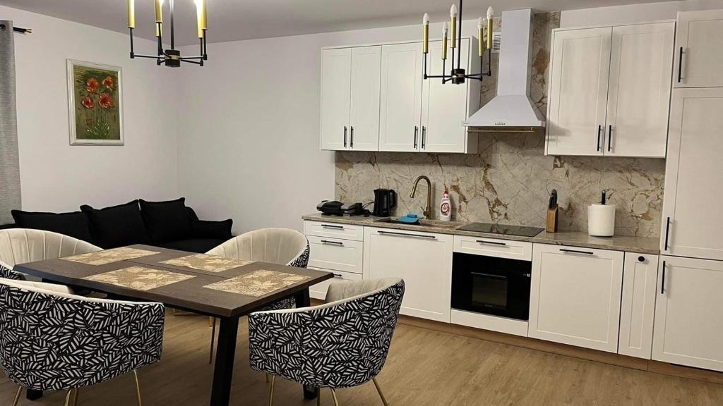 uma cozinha com armários brancos e uma mesa e cadeiras em Apartament Złoty 4 em Zblewo