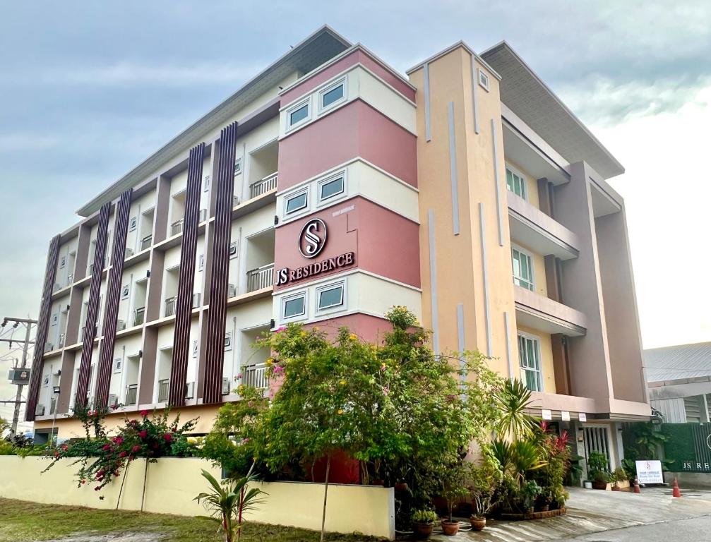un grand bâtiment rose avec un panneau sur lui dans l'établissement JS Residence Krabi, à Krabi