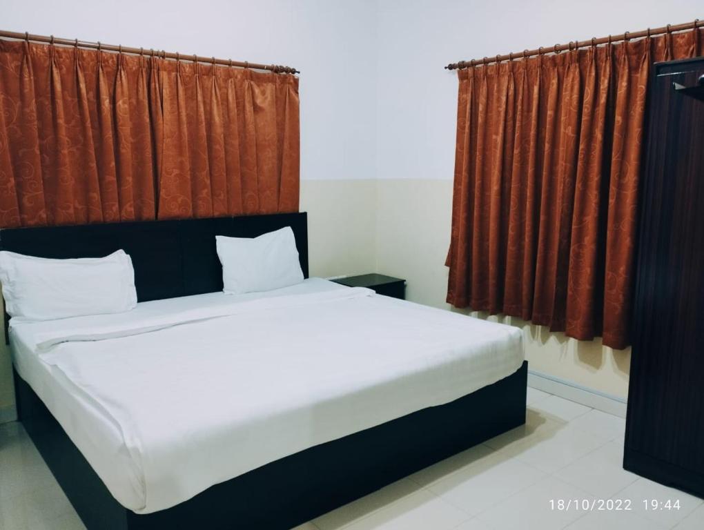 a bedroom with a large bed with red curtains at Al Basateen Hotel Apartment in Sur