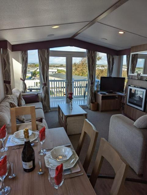 Caravan Littlesea Haven Weymouth Amazing Views في ويماوث: غرفة معيشة مع طاولة مع كؤوس للنبيذ عليها