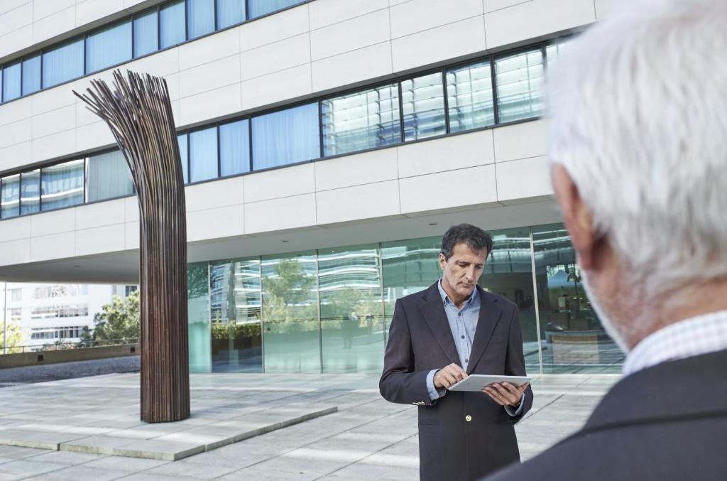a man standing in front of a building looking at a tablet at Martinhal Lisbon Oriente in Lisbon