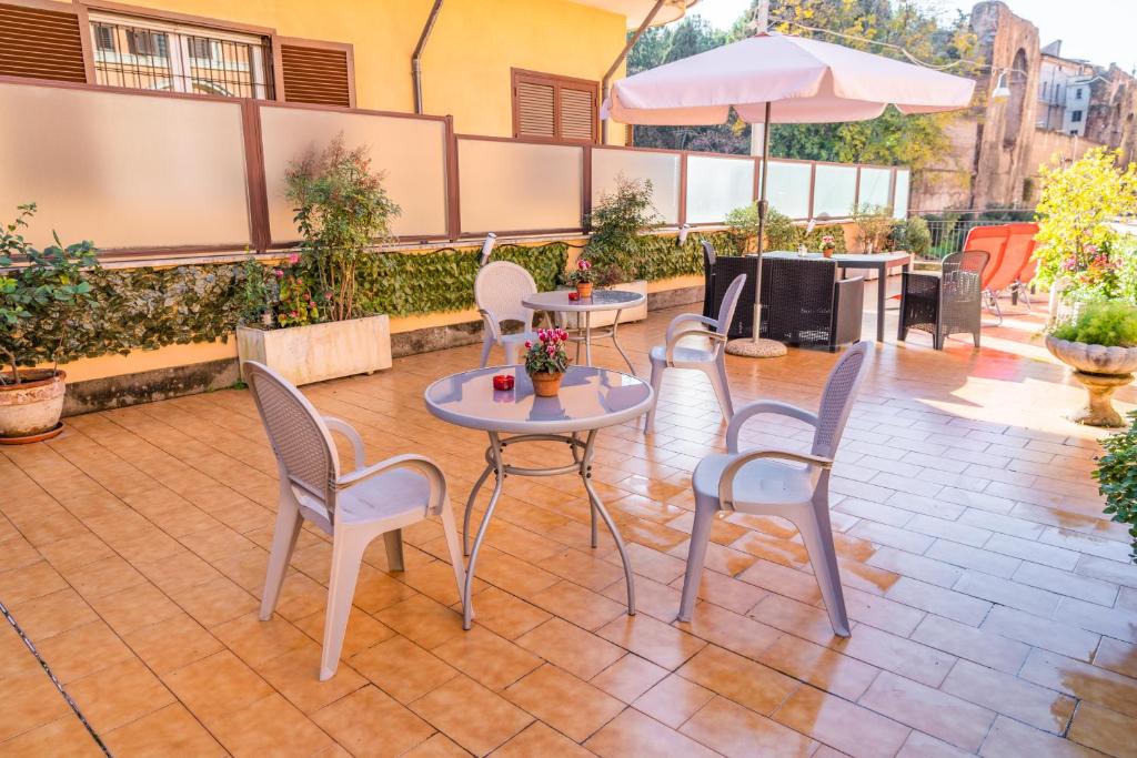 a patio with chairs and tables and an umbrella at Le Terrazze di San Giovanni in Rome