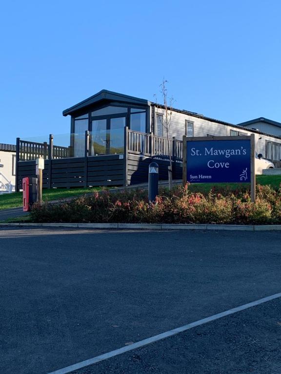 a building with a sign on the side of a road at Mawgan Pads Lazy Days Lodge in Mawgan Porth