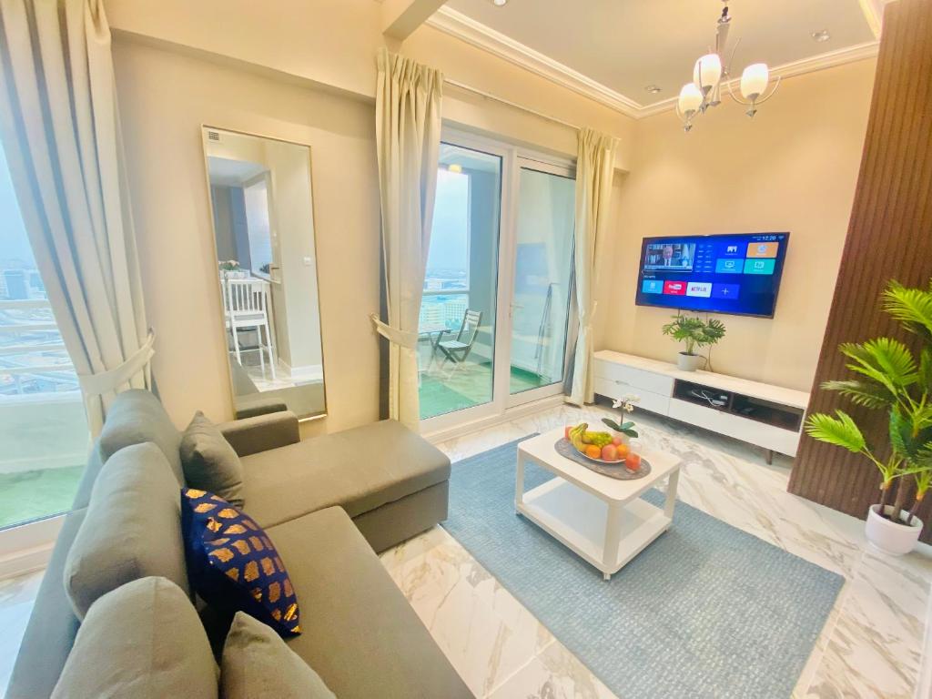 a living room with a couch and a tv at Manchester Regency - 2BR Apartment in Dubai Marina in Dubai