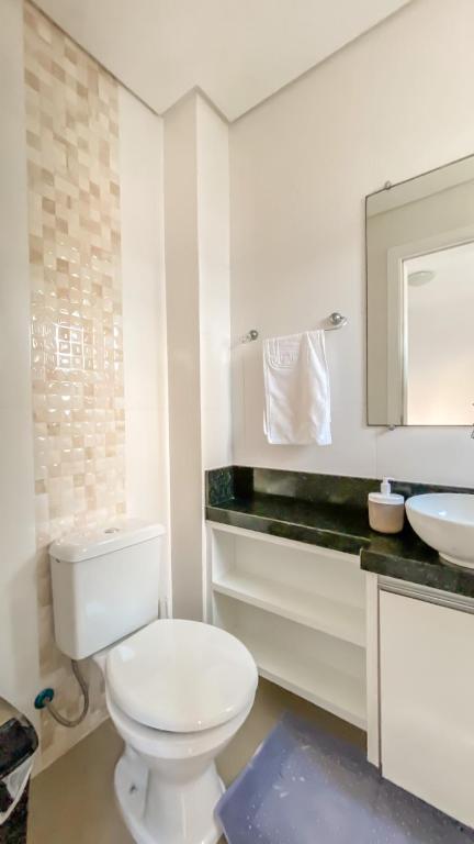 a white bathroom with a toilet and a sink at Apto Praia Brava : 2 suítes in Itajaí