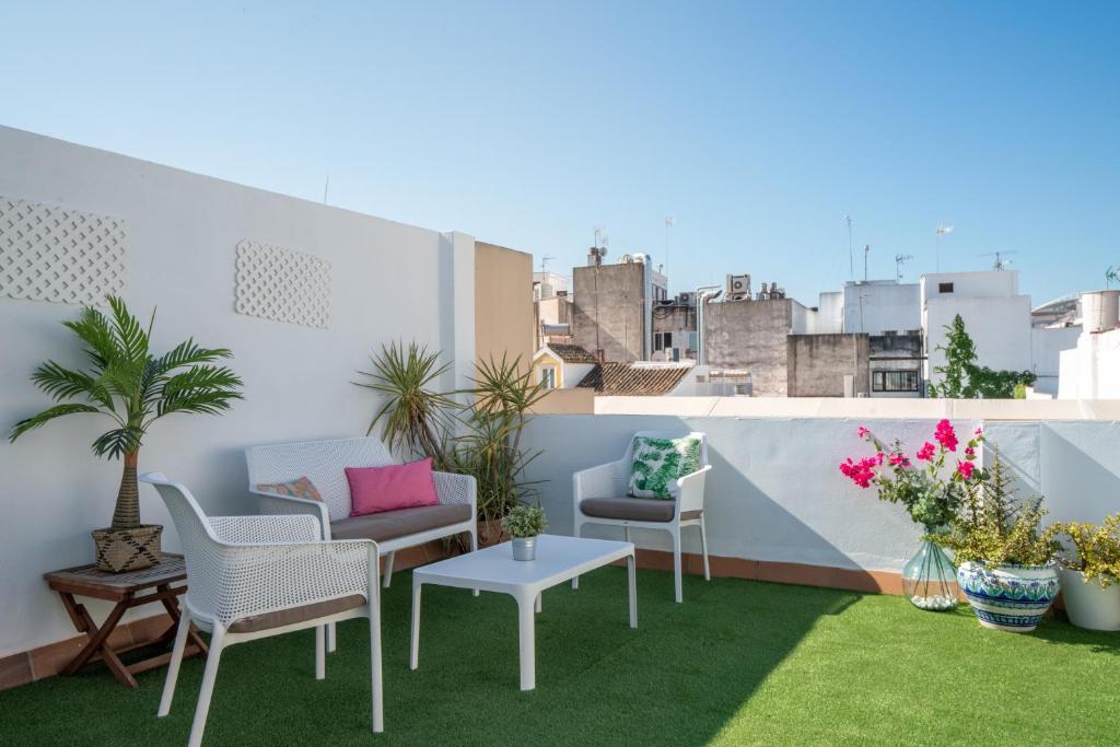 un patio en la azotea con sillas, mesas y plantas en Apartments Olé - Albareda 24, en Sevilla