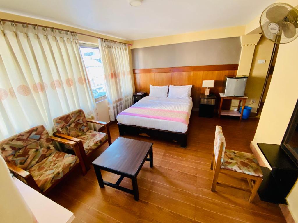 1 dormitorio con cama, sofá y mesa en Hotel Vajra Inn & Apartments, en Pokhara