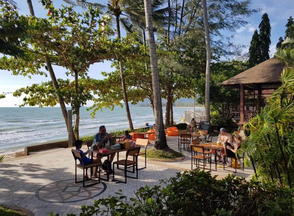 grupa ludzi siedzących przy stołach przy plaży w obiekcie Chill Inn Lipa Noi Hostel and Beach Cafe w mieście Koh Samui