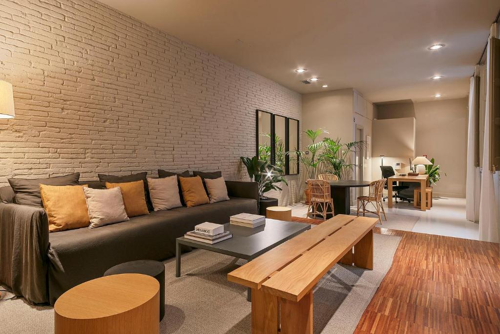 a living room with a couch and a brick wall at Uma Suites Pau Claris in Barcelona
