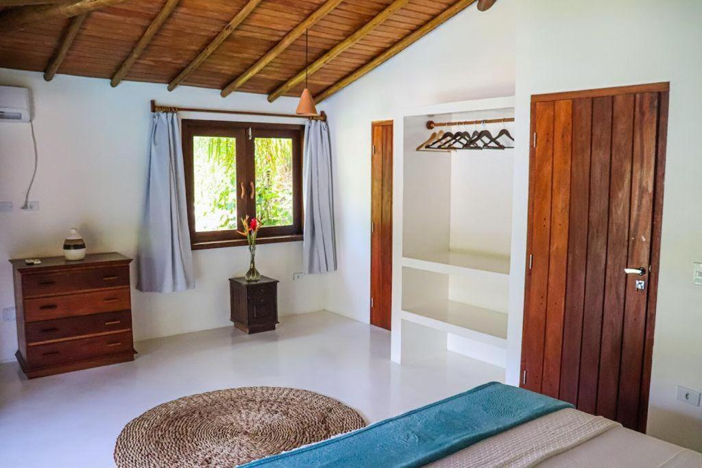 ein Schlafzimmer mit einem Bett, einem Fenster und einer Kommode in der Unterkunft Suites Taipe in Trancoso