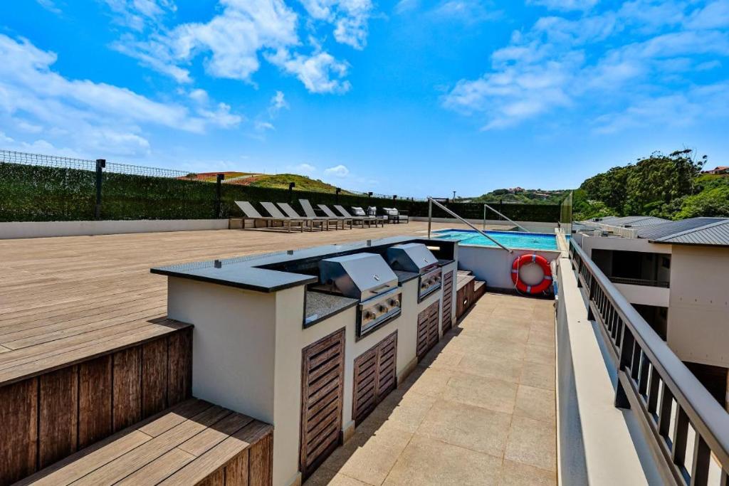un balcon avec une terrasse sur laquelle se trouve un bateau. dans l'établissement Zimbali Lakes Boulevard Suites, Unit148, à Ballito