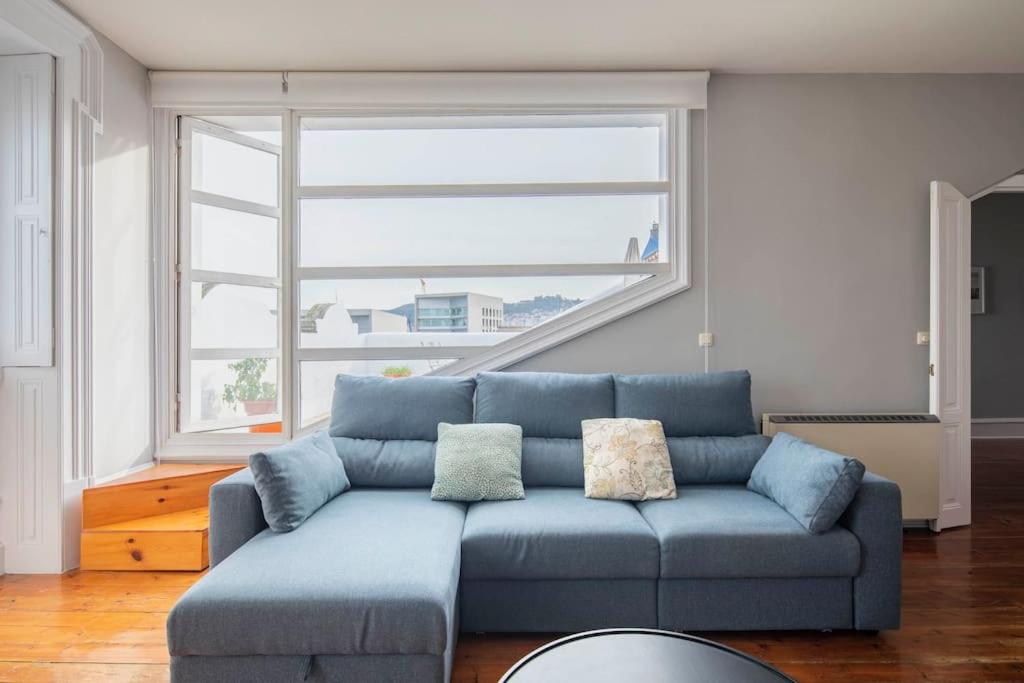 un divano blu in soggiorno con una grande finestra di Céntrico Ático frente al Mar a Vigo