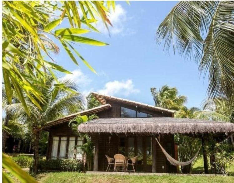 uma casa com duas cadeiras e uma rede em frente em Siri Paraiso Hotel em Touros