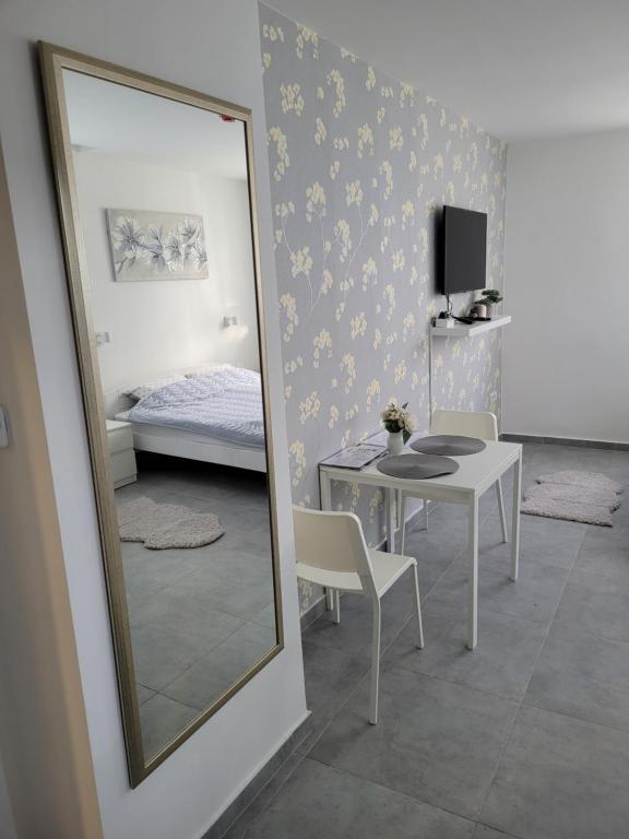 a mirror in a room with a table and a bed at Oaza apartmani 1 in Senta