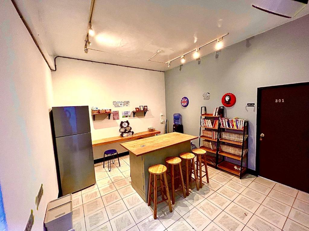 a kitchen with a counter and a refrigerator and stools at Time Capsule in Taitung City