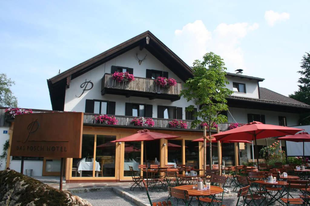 a restaurant with tables and umbrellas in front of a building at Das Posch Hotel in Oberammergau