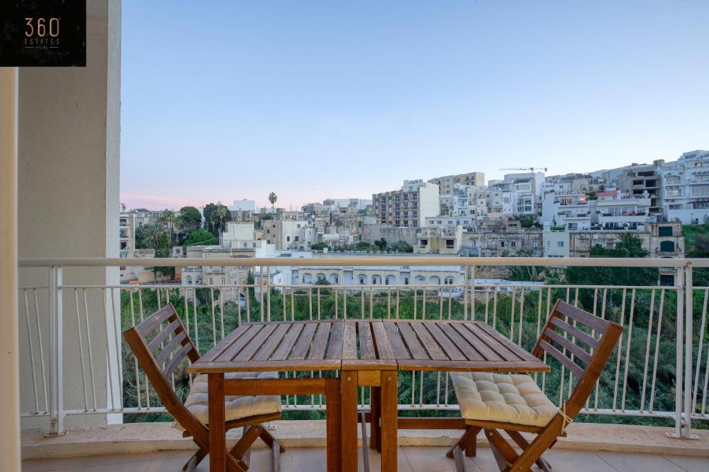 uma mesa de madeira e cadeiras numa varanda com uma cidade em Green Oasis: Home with Breathtaking View w/parking by 360 Estates em Sliema